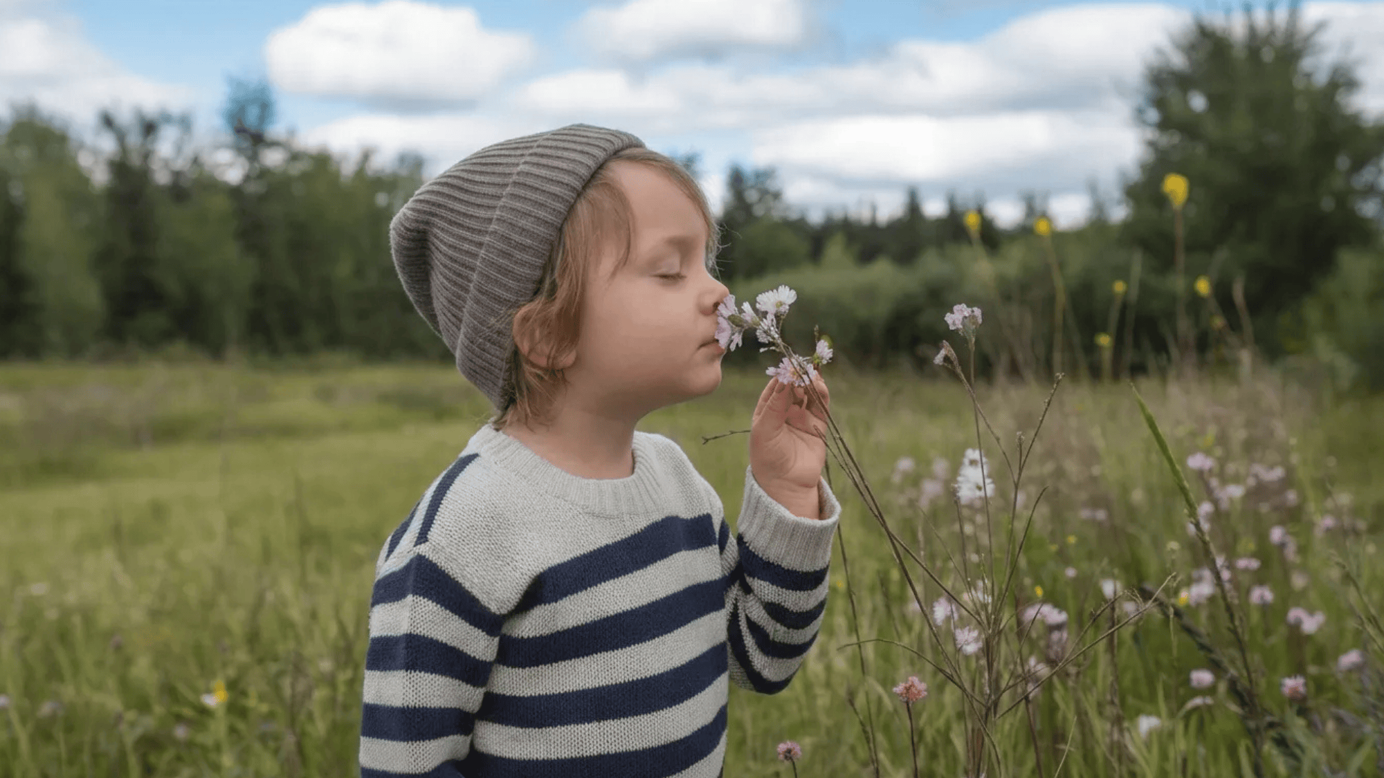 a boy smelling flowers in a garden