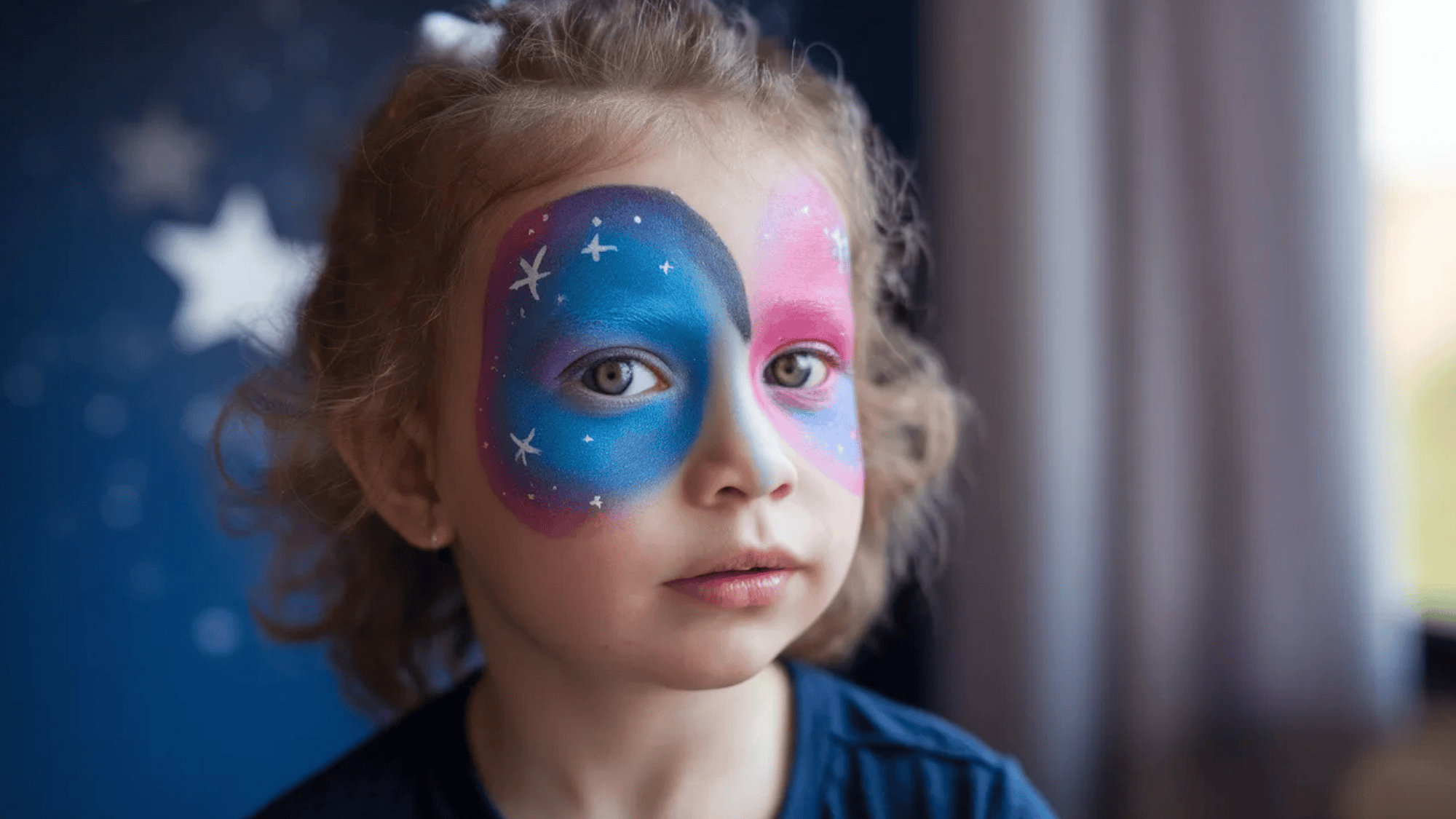 a galaxy theme painted on a kid's face with blue, white, and pink shades