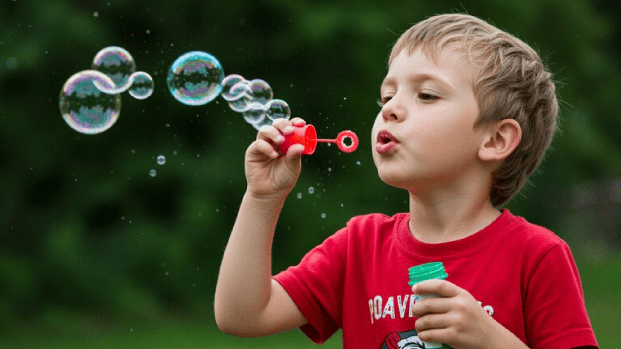 a kid blowing bubbles in the park