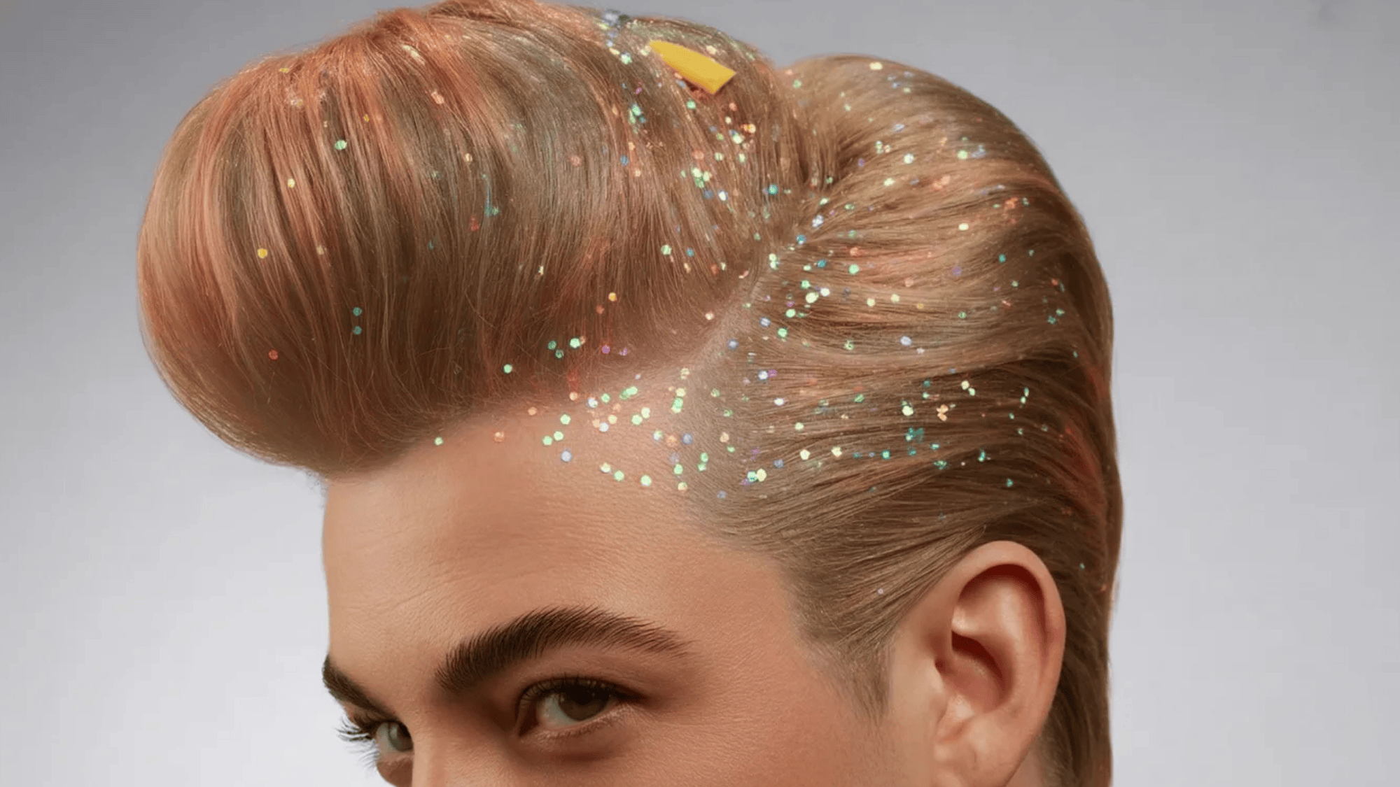 a person with a styled voluminous pompadour hairstyle, featuring colorful glitter specks