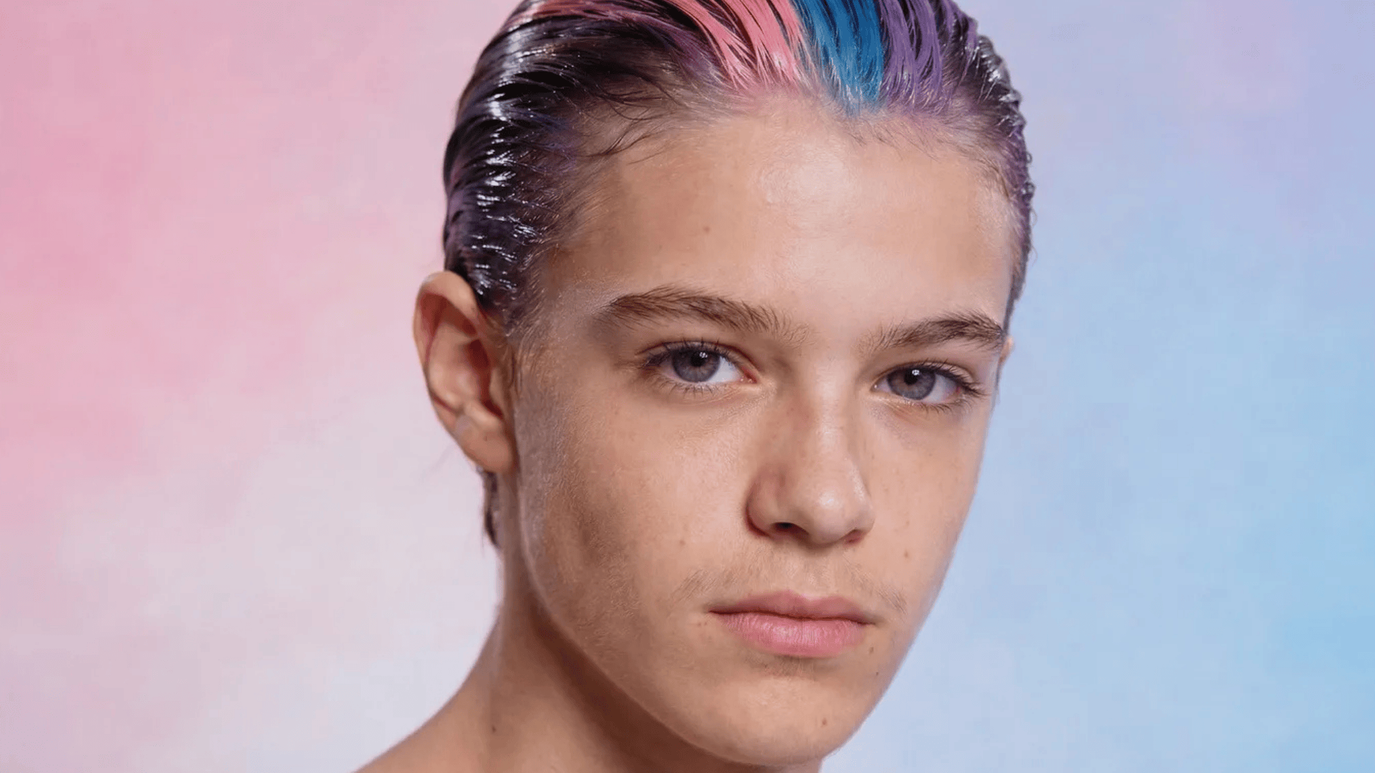 a person with short, styled hair in vibrant pink and blue hues