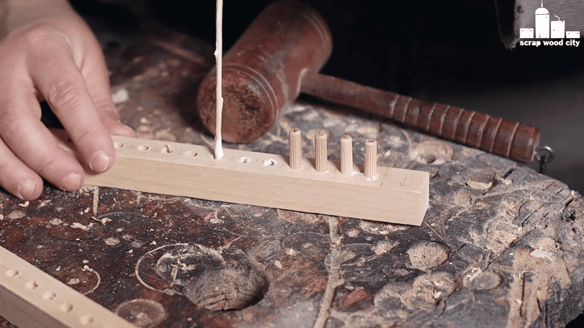 a wooden loom frame being assembled with screws and glue, with a person holding it in place.