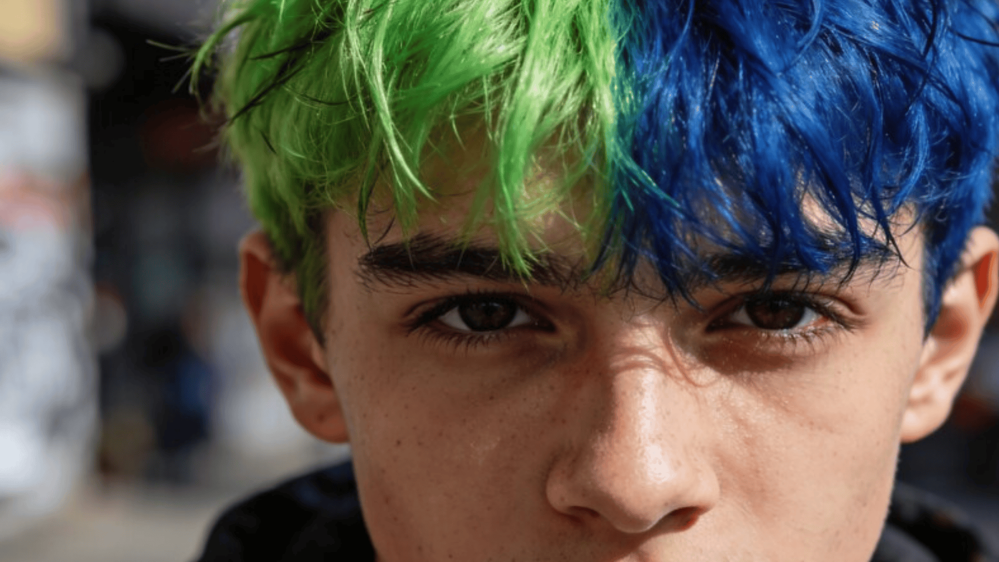 a young person with vibrant green and blue dyed hair
