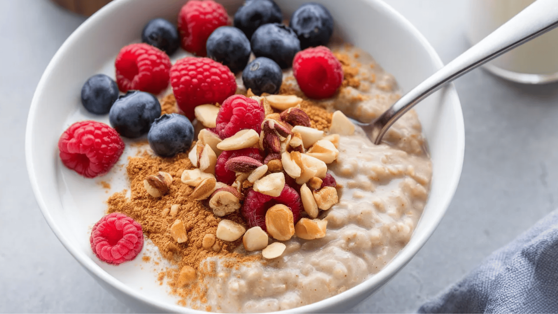 bowl of oatmeal topped with fresh raspberries, blueberries, chopped almonds, and a sprinkle of cinnamon