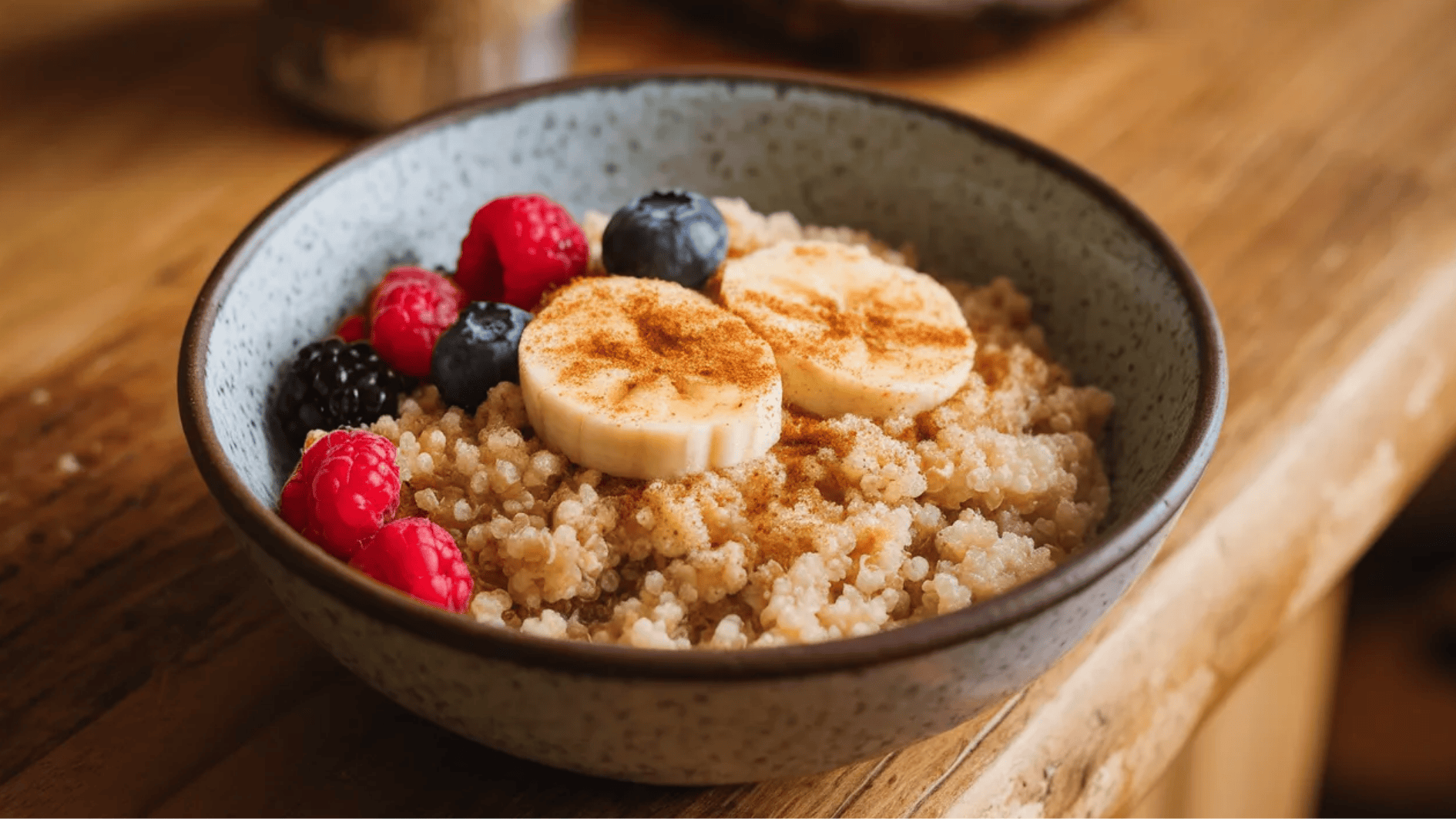 bowl of quinoa topped with banana slices, mixed berries, and a sprinkle of cinnamon