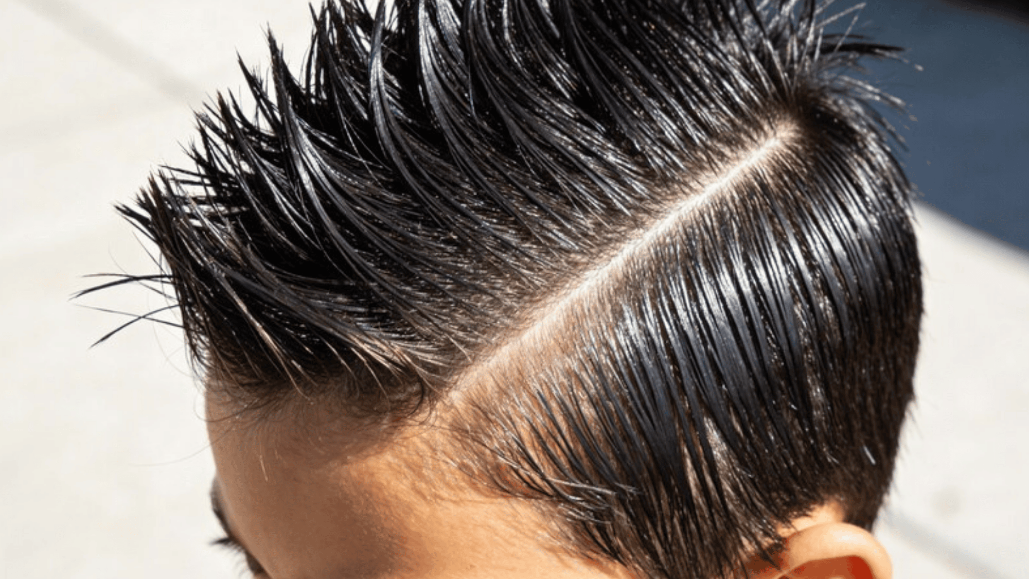 boy's slicked-back spiky hairstyle with a neat side part, showing the shine and texture of his hair
