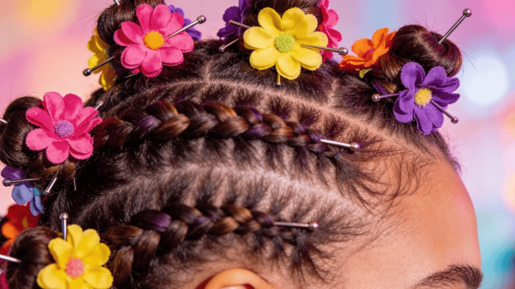 braided hairstyle with colorful flower clips in bright pink, yellow, and purple, creating a fun and vibrant look