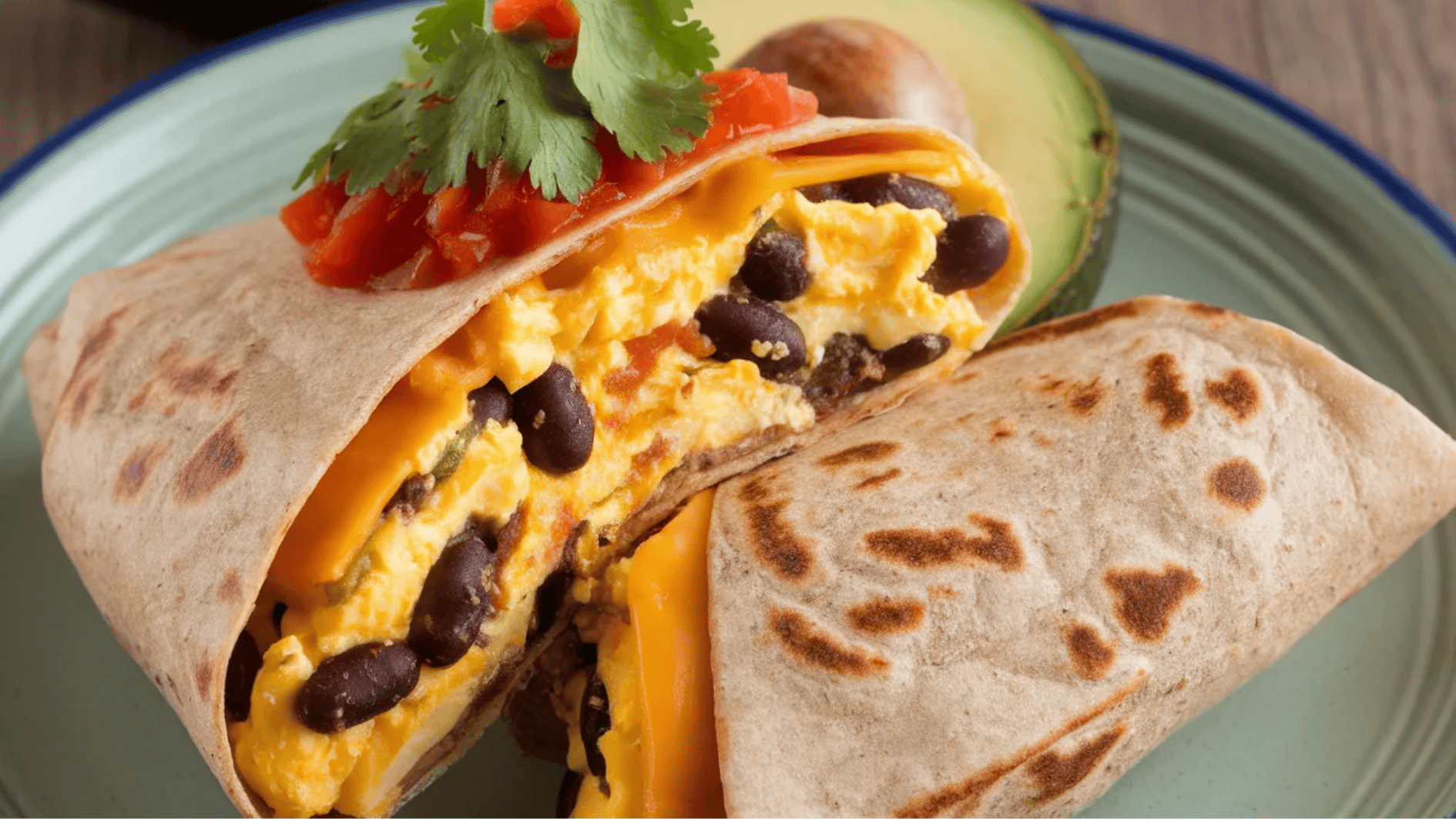 breakfast burrito filled with scrambled eggs, black beans, cheddar cheese, and topped with salsa and cilantro