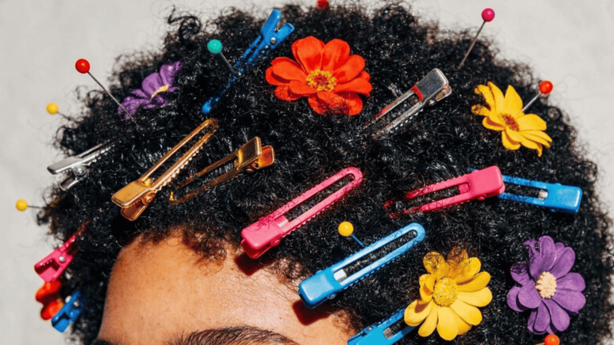 close-up of natural curly hair adorned with colorful hair clips and flowers, creating a playful and vibrant look