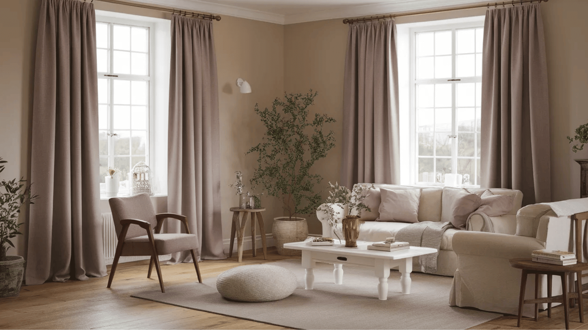 cozy living room with soft neutral tones, featuring a comfortable sofa, decorative pillows, and plants, along with elegant curtains