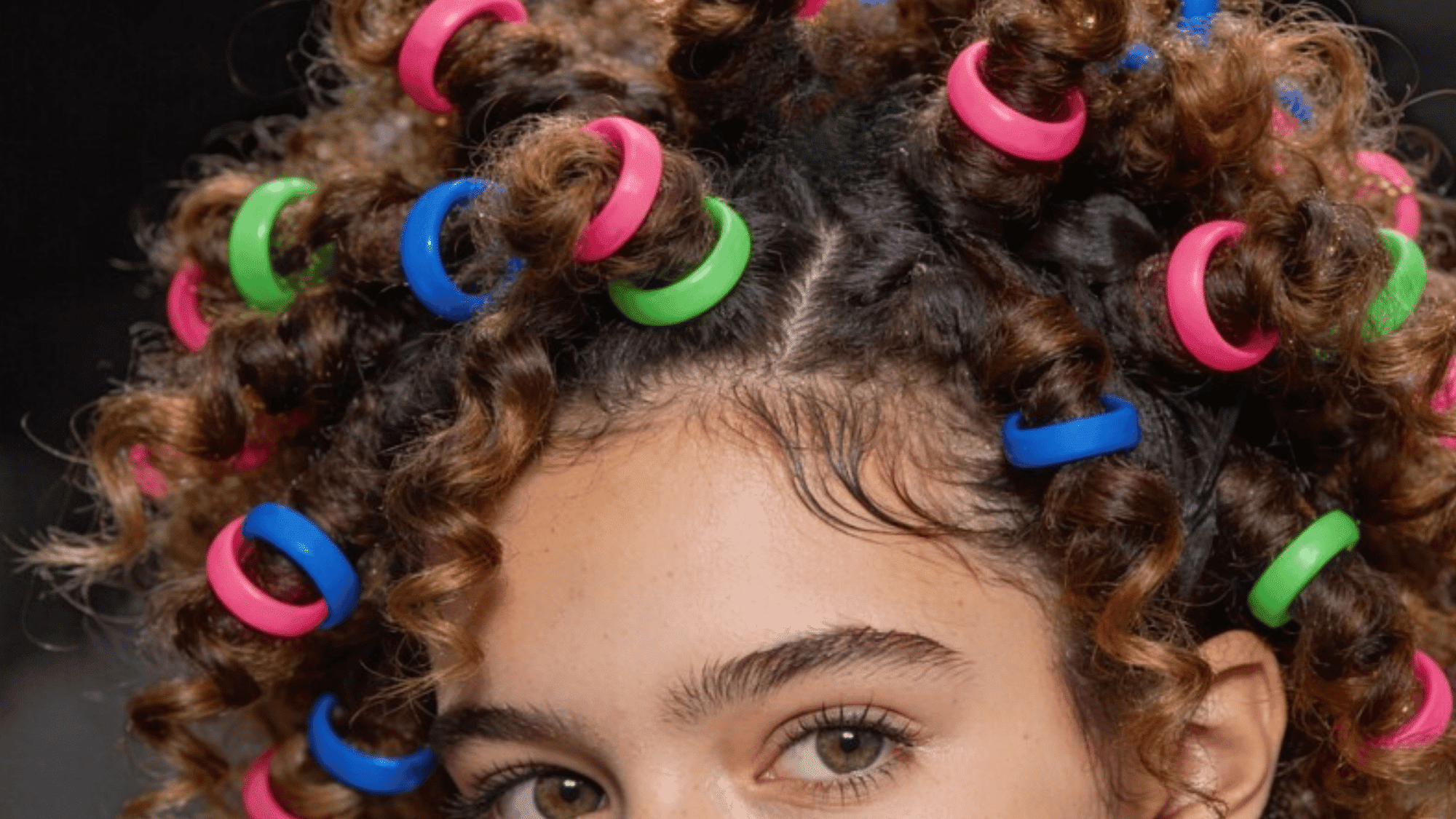 curly hair styled with colorful spiral curlers, creating a fun and vibrant look