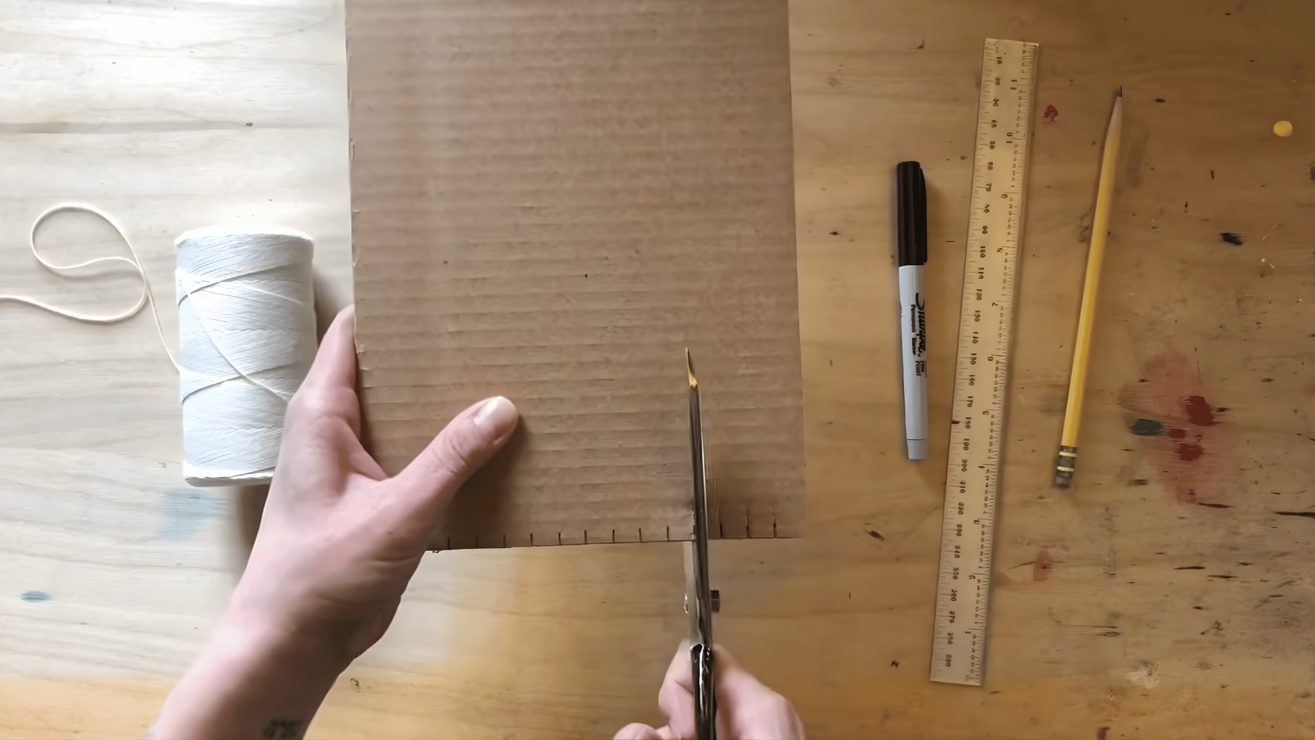 cutting the notches along the bottom of the cardboard with scissors to create spaces for the warp threads