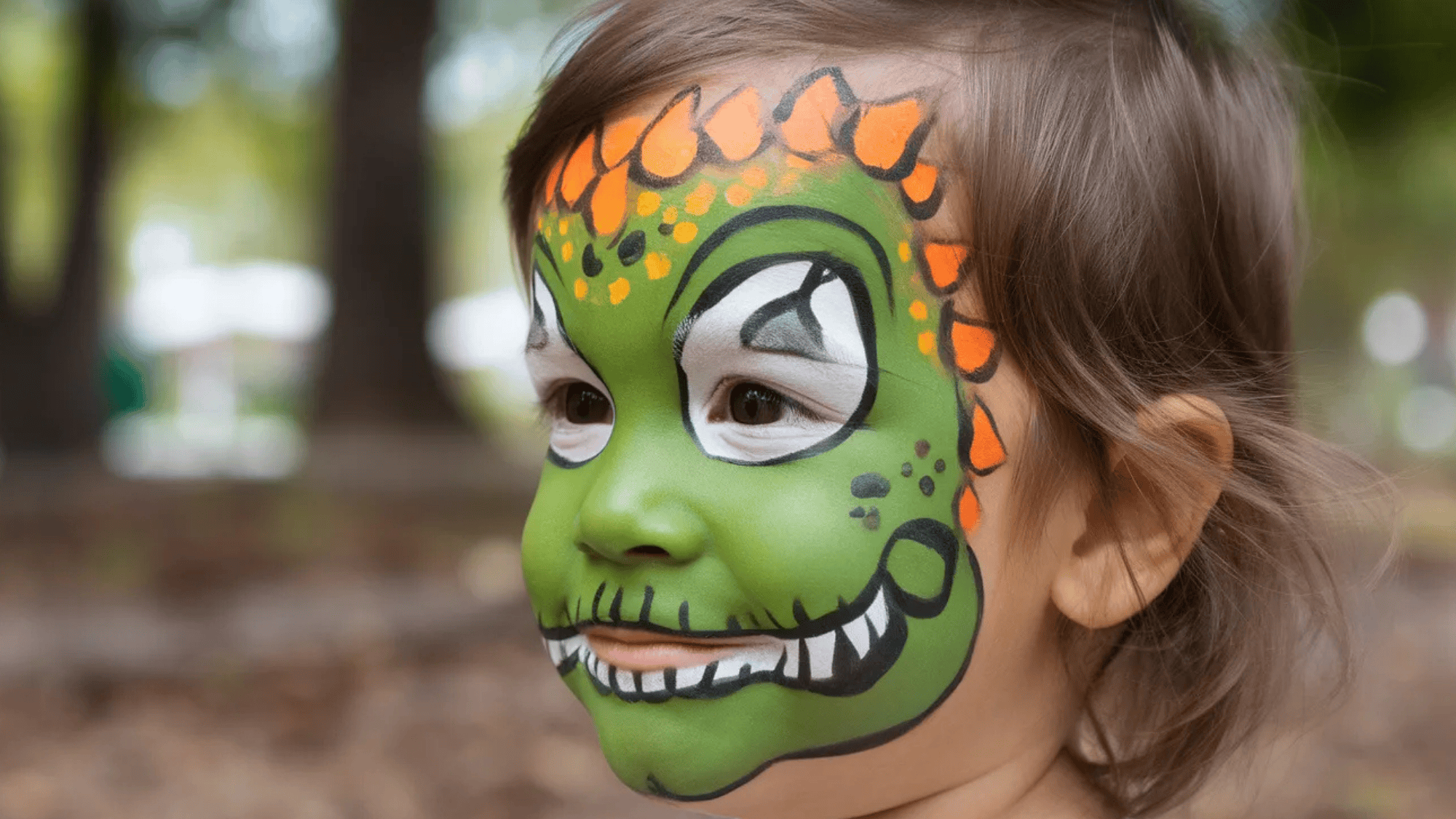 dinosaur face paint on kid with green body and orange horns (1)