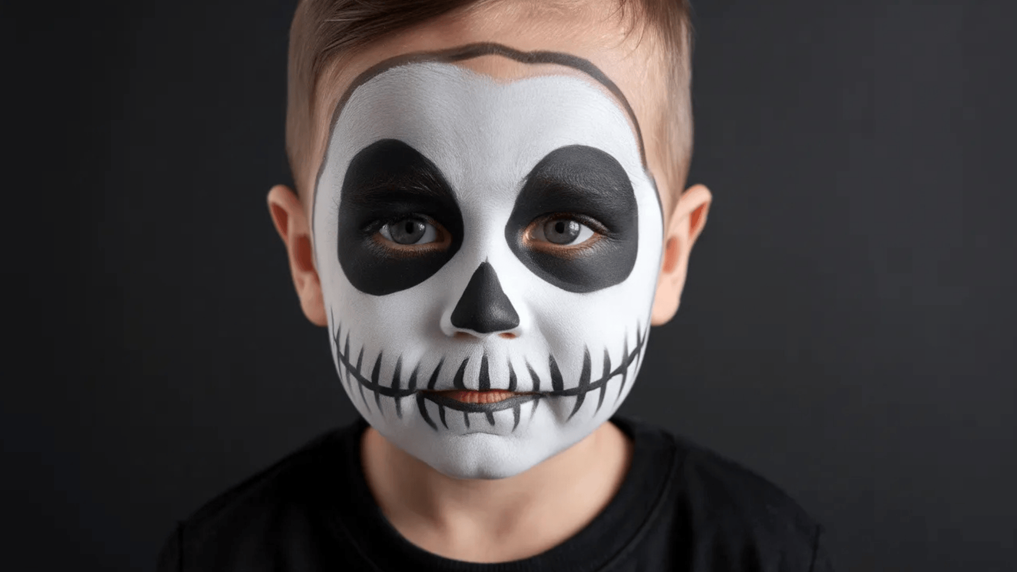 kid's face painted as a skeleton with black and white colors