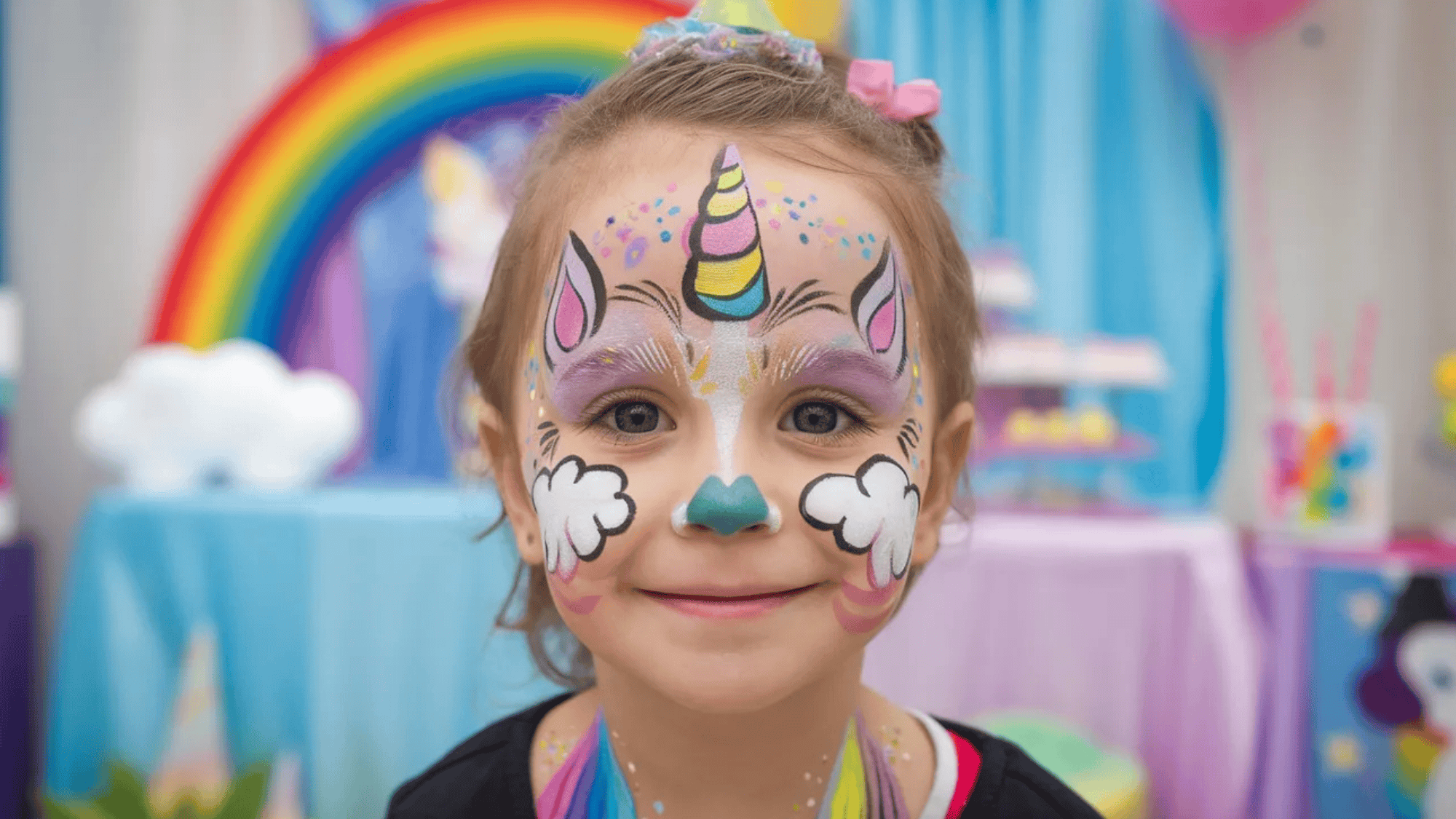 kid's face painted in a unicorn theme