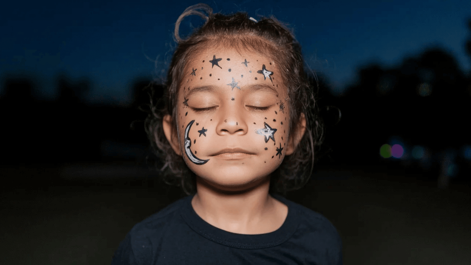 kid's face painted with black and white colors to make moon and stars