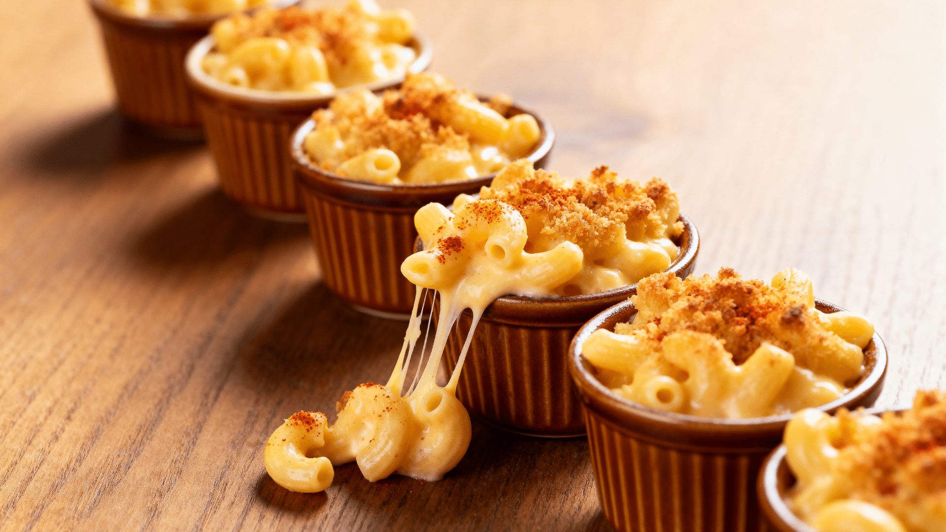 mac and cheese cups baked in muffin tins with golden cheesy tops arranged on a serving table
