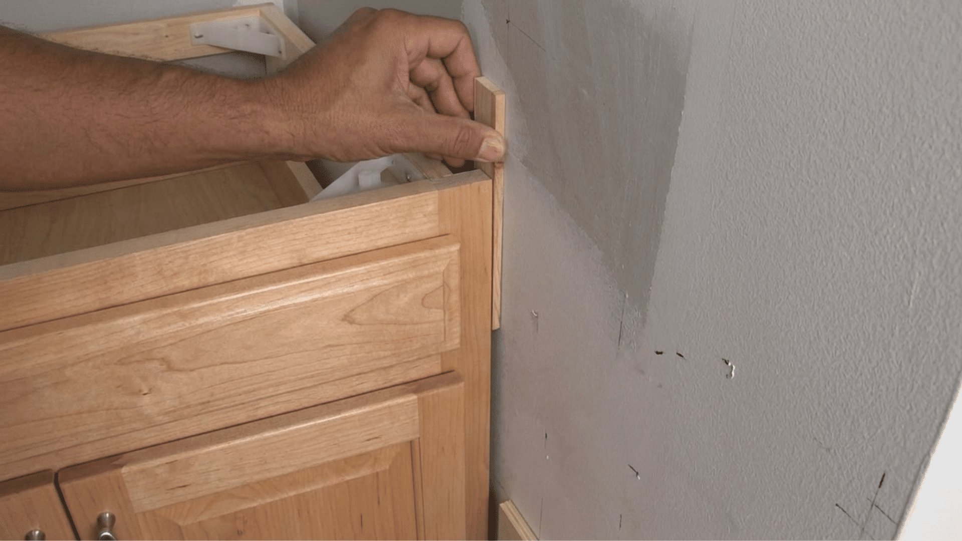 measuring, cutting, and shimmed filler strips being used to fill gaps between the wall and cabinet.