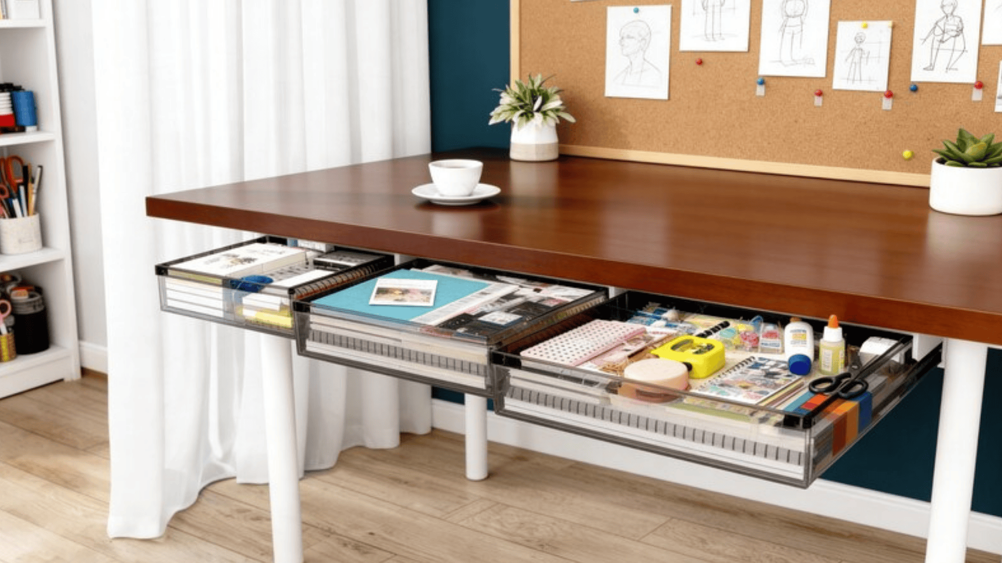 modern desk with an open drawer filled with crafting supplies like paper, glue, and scissors, alongside a cup, potted plants, and a corkboard with design sketches on the wall