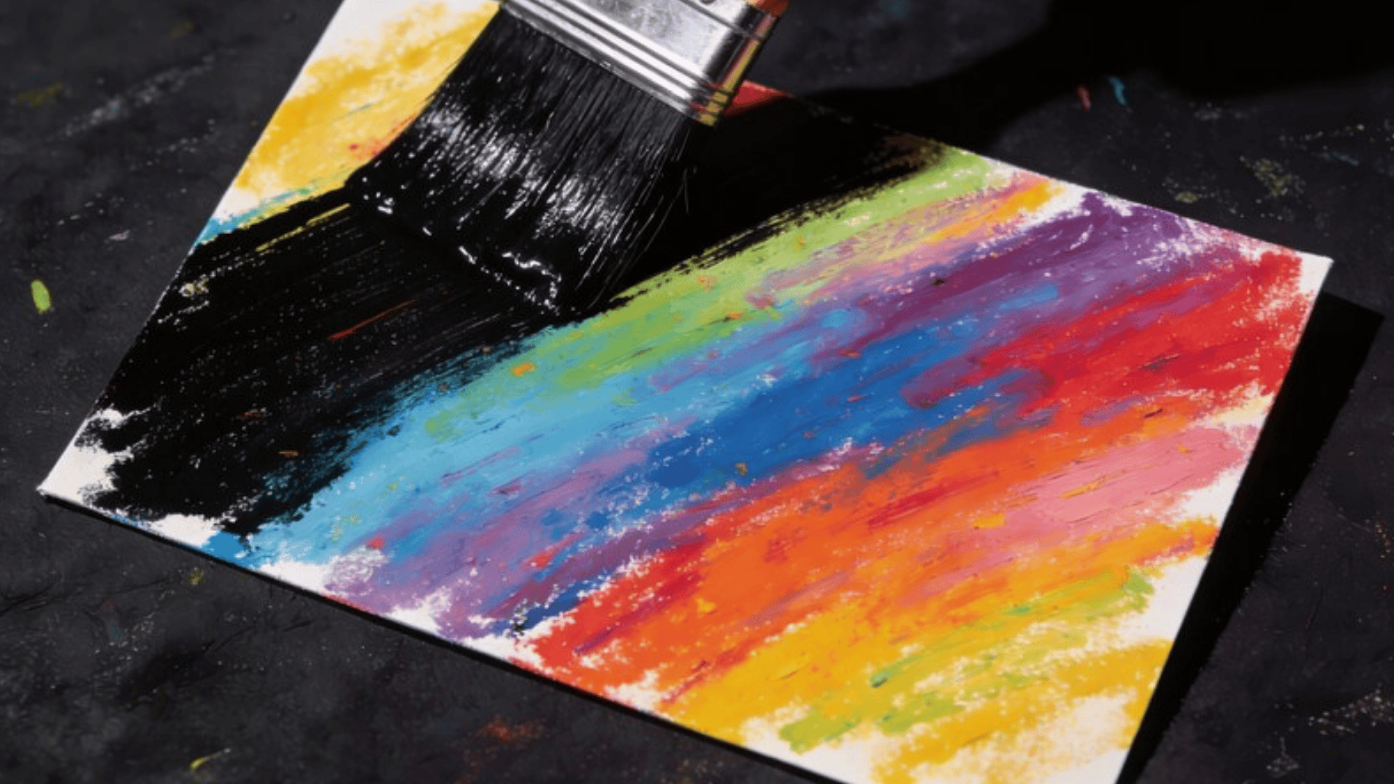 one broad brush painting a cardstock with black paint