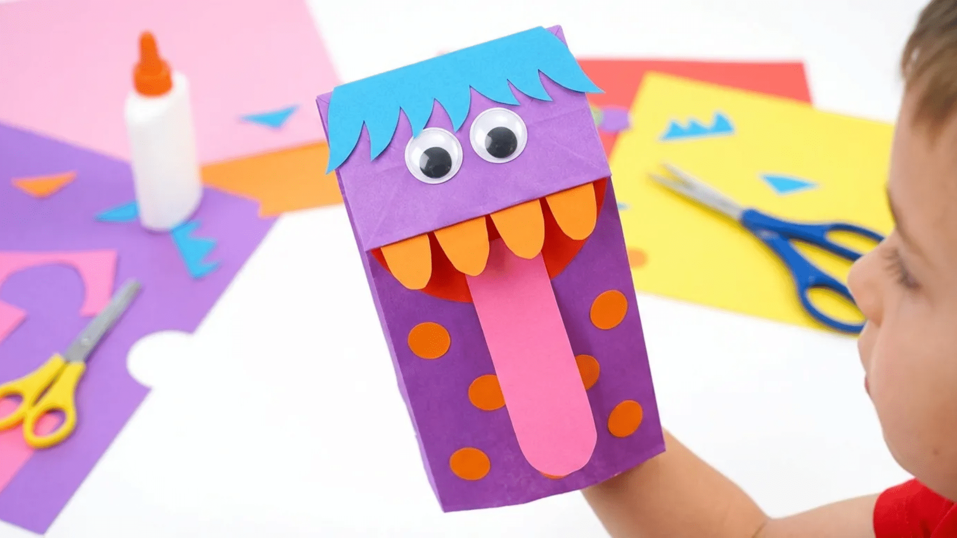 paper lunch bag with a drawn face, paper hair and paper tongue made into a hand puppet