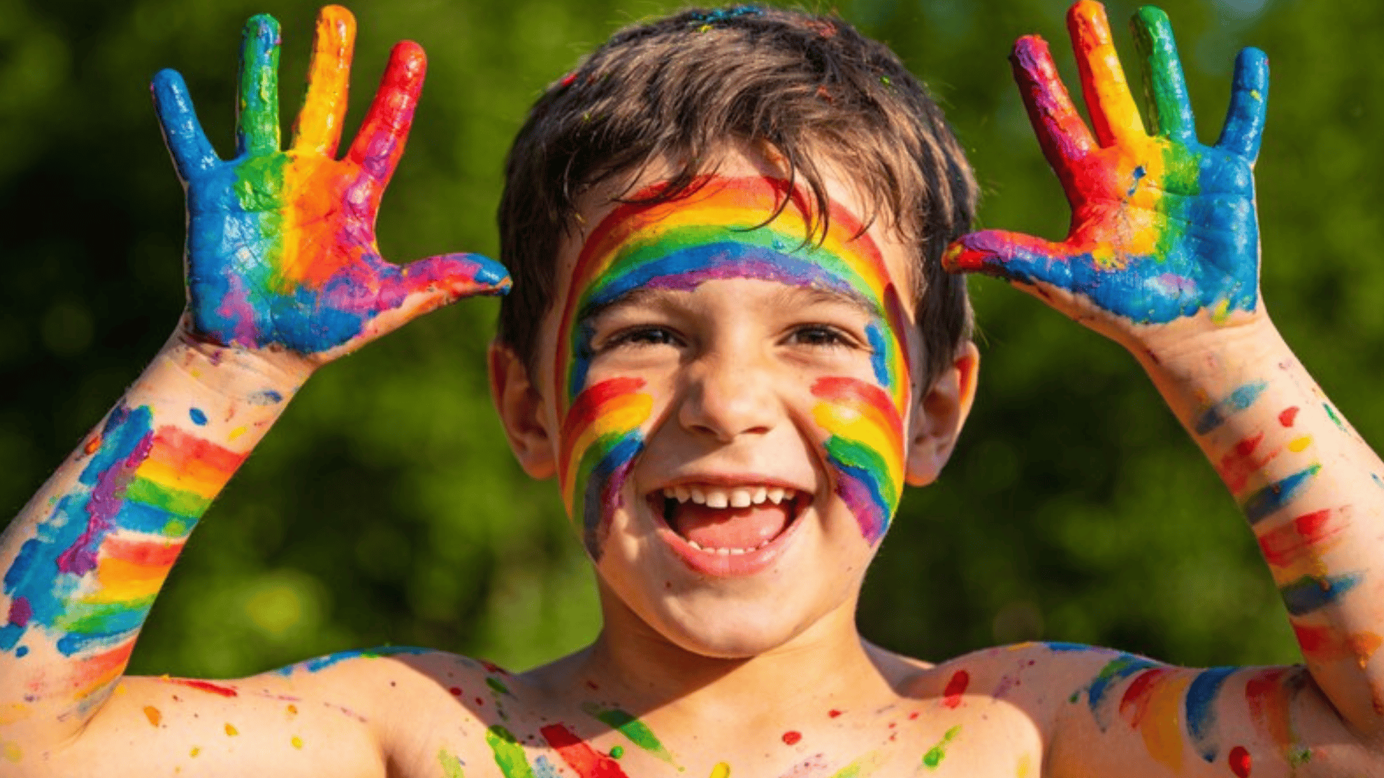 rainbow paint on a real kid, vibrant multicolored streaks across face and arms, playful messy splashes