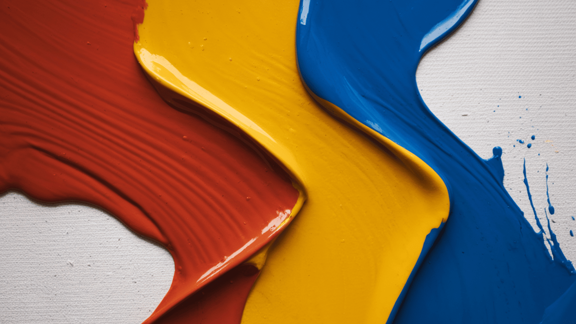 red, yellow, and blue acrylic paint streaks spread on a white canvas texture.