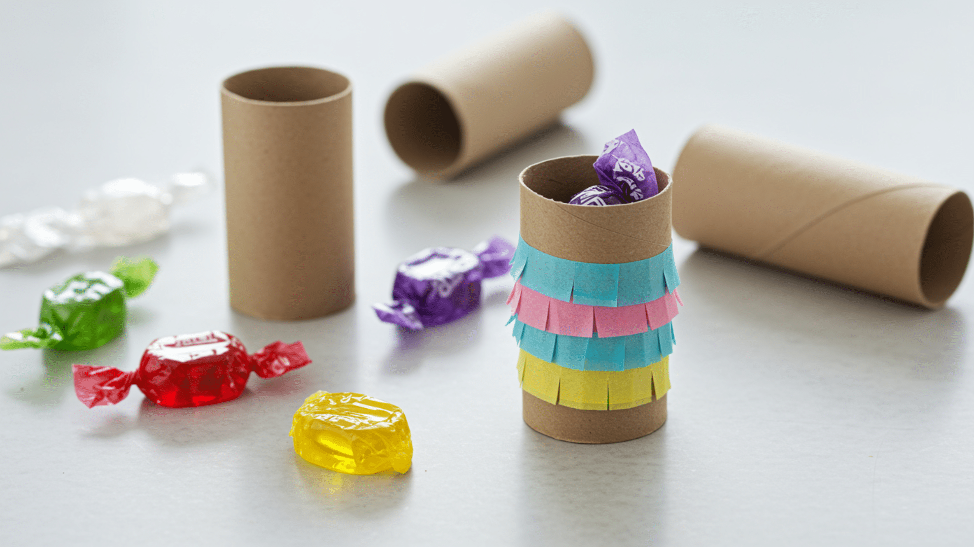 small paper roll piñatas covered in fringed tissue paper with sealed ends.
